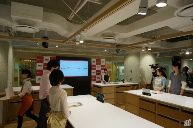 　NTTドコモとABC Cooking Studioは2月7日、事業戦略に関する説明会を開催し、海外と遠隔レッスンもできる丸の内スタジオを披露した。2013年10月25日、ドコモは料理教室大手の「ABCクッキングスタジオ」（ABC）を買収することを発表している。新たな事業展開に向け、渋谷と丸の内のクッキングスタジオをリニューアルし、スタジオに大型のモニタやタブレットを設置した。